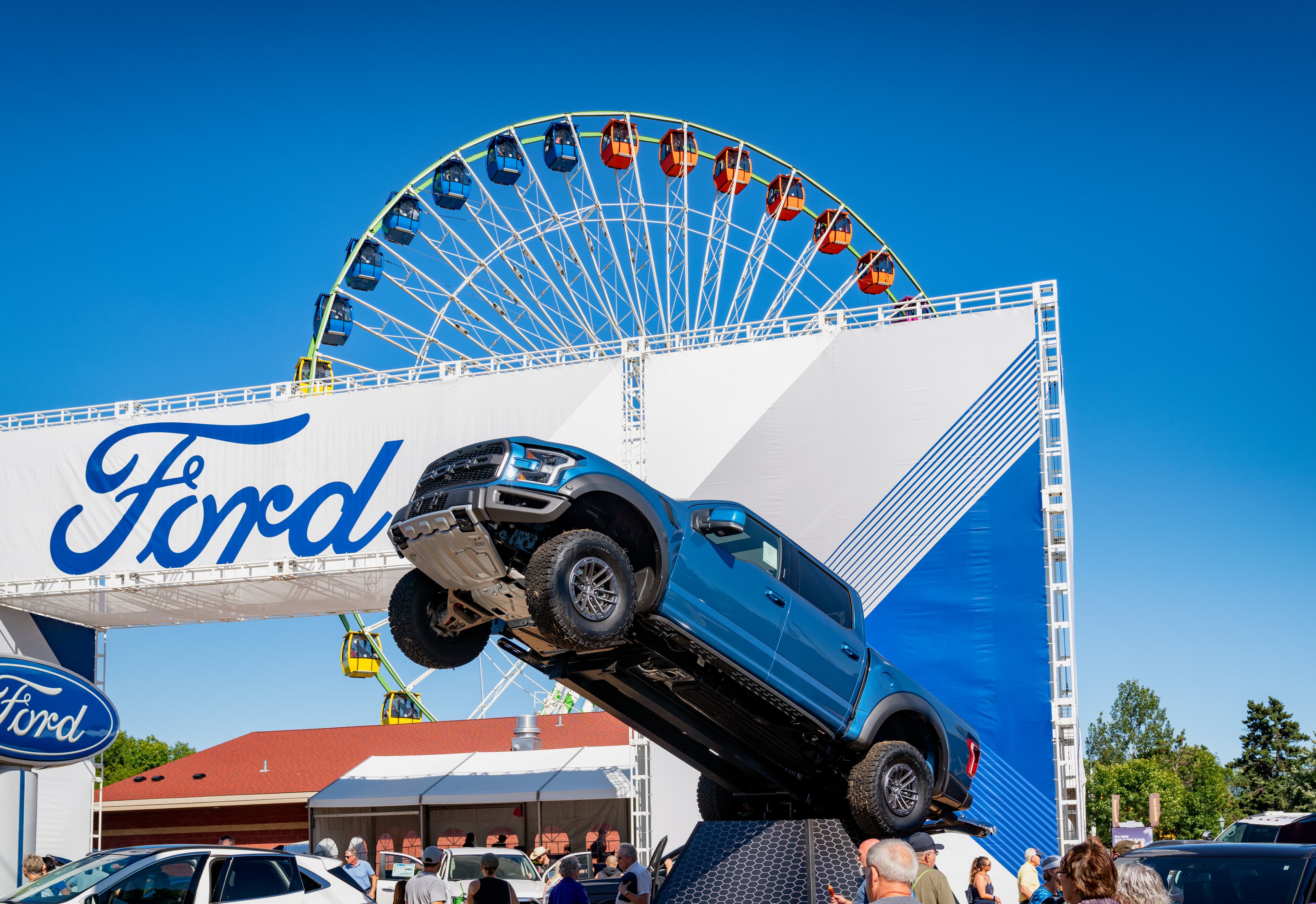 Blue second-gen Raptor tipped up on a display ramp at the Minnesota State Fair with the Ferris wheel behind it