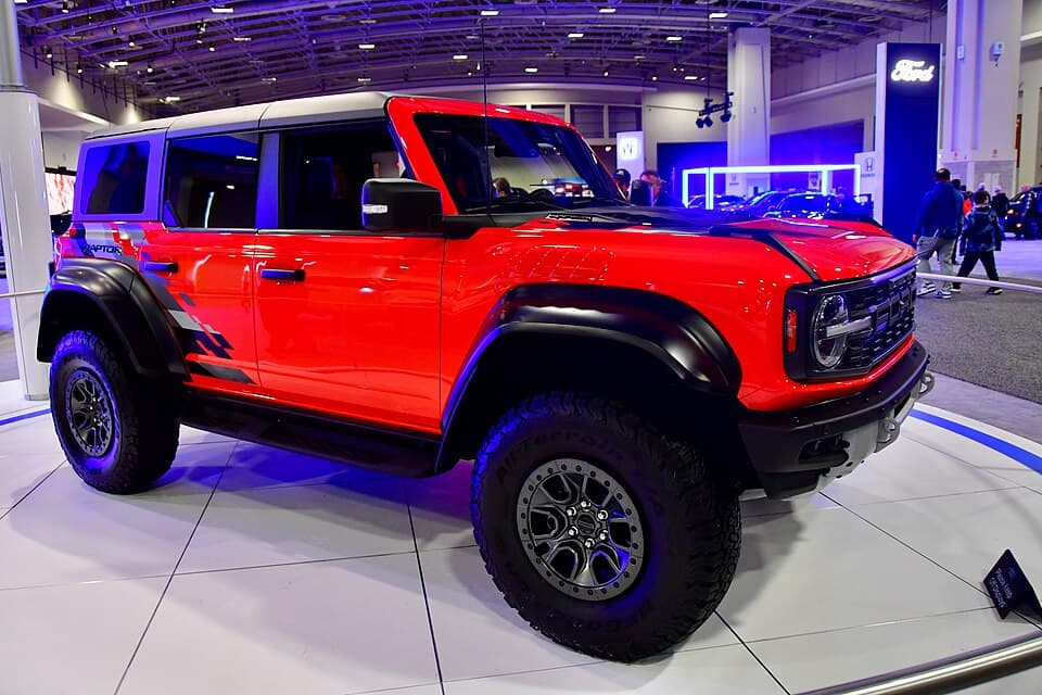 Red Bronco Raptor on the stand at the 2024 Washington Auto Show, front three-quarter.
