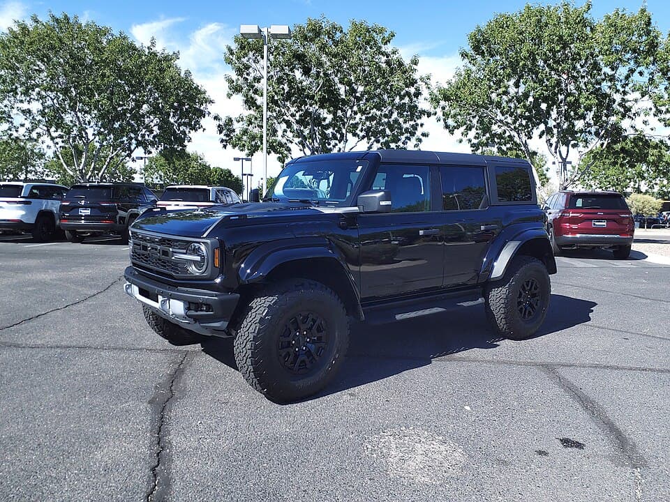 Dark 2024 Bronco Raptor on a dealer lot in Gilbert, Arizona, front three-quarter in flat daylight.