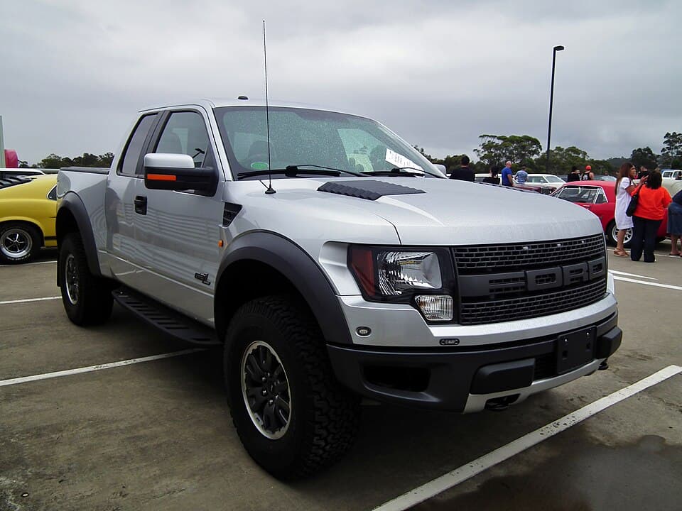 2012 SVT Raptor SuperCab in silver, front three-quarter at an Australian car show — a factory SuperCab on stock wheels.