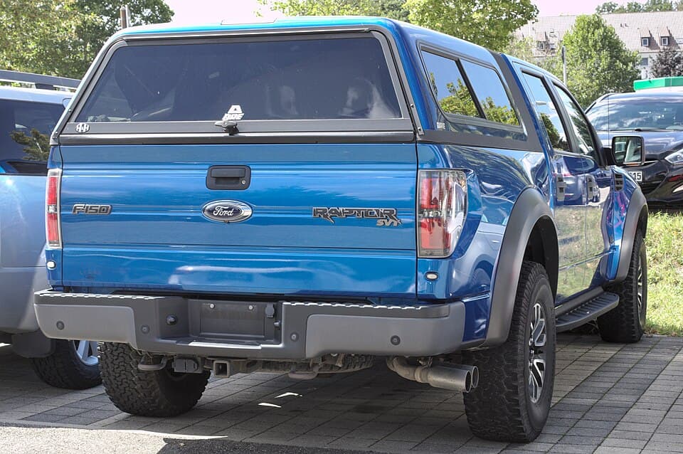 Blue first-gen SVT Raptor with an aftermarket bed canopy, shot from the rear on a street in Stuttgart-Vaihingen, Germany.