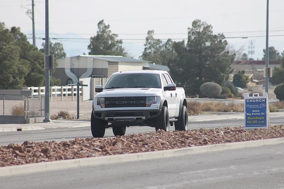 White first-gen Raptor caught mid-drive on North Jones Boulevard in Las Vegas, front three-quarter, stock ride height and stock 35-inch BFGs.