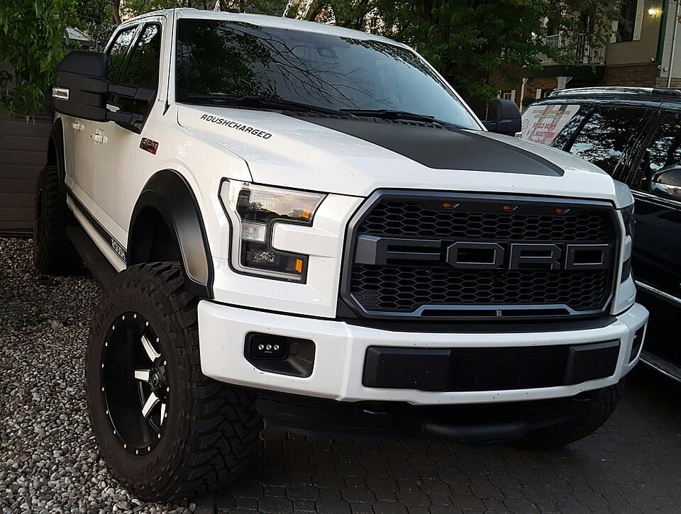 2017 Raptor SuperCrew in white with a black hood wrap and aftermarket wheels, front three-quarter in Laval, Québec.