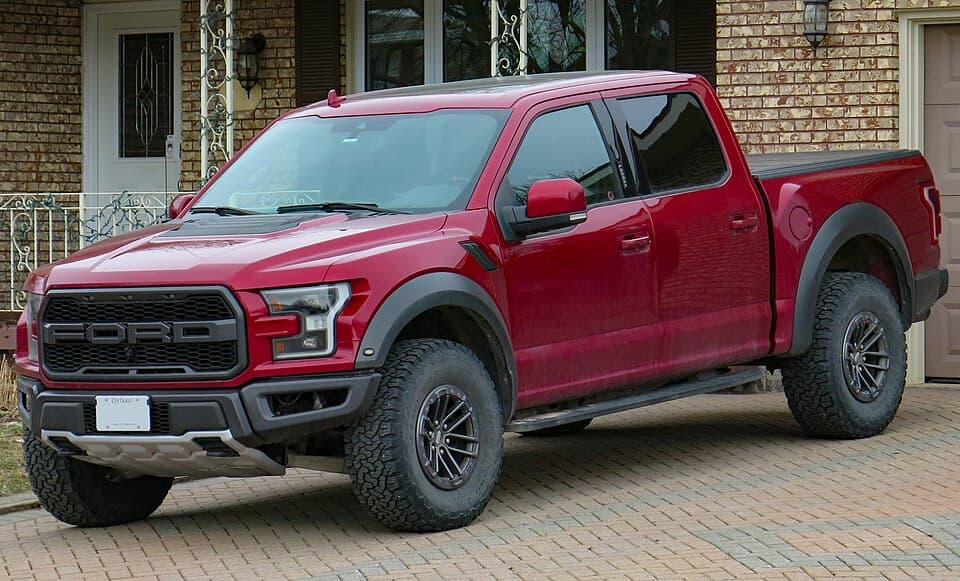 2019 Raptor 4x4 SuperCrew with the 5.5-foot box in Ruby Red Metallic Tinted Clearcoat, front-left three-quarter on a residential driveway in Ontario.