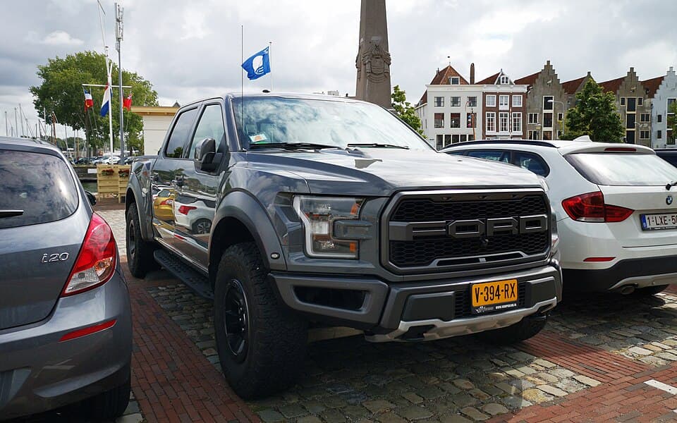 Grey 2018 Raptor SuperCrew on cobbles in Amersfoort, Netherlands, front three-quarter with the block-letter FORD grille and C-clamp headlights.