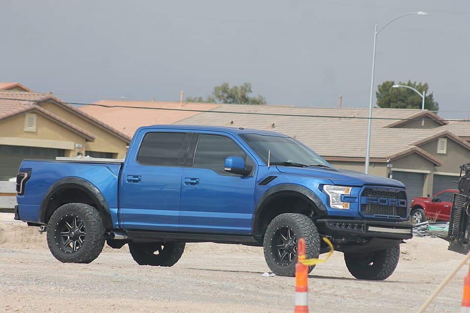 Blue second-gen Raptor parked on a dirt lot in Las Vegas, side profile — a stock truck being used the way it was intended.
