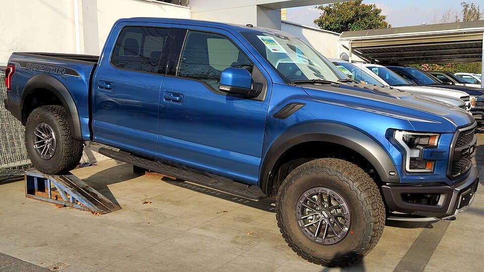 Blue 2019 Raptor on loading ramps, side-on — a good view of the wheel-arch clearance and the rear leaf-sprung axle.