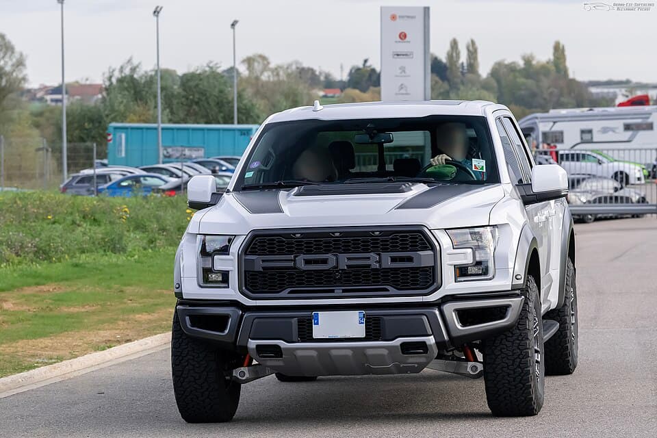 White second-gen Raptor SuperCab photographed head-on in France, showing the marker lights, front skid plate and the extra front track.