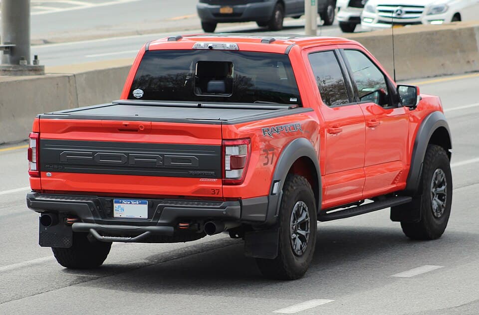 Code Orange 2021 Raptor with a tonneau cover, rear three-quarter on a street in Flushing, Queens.