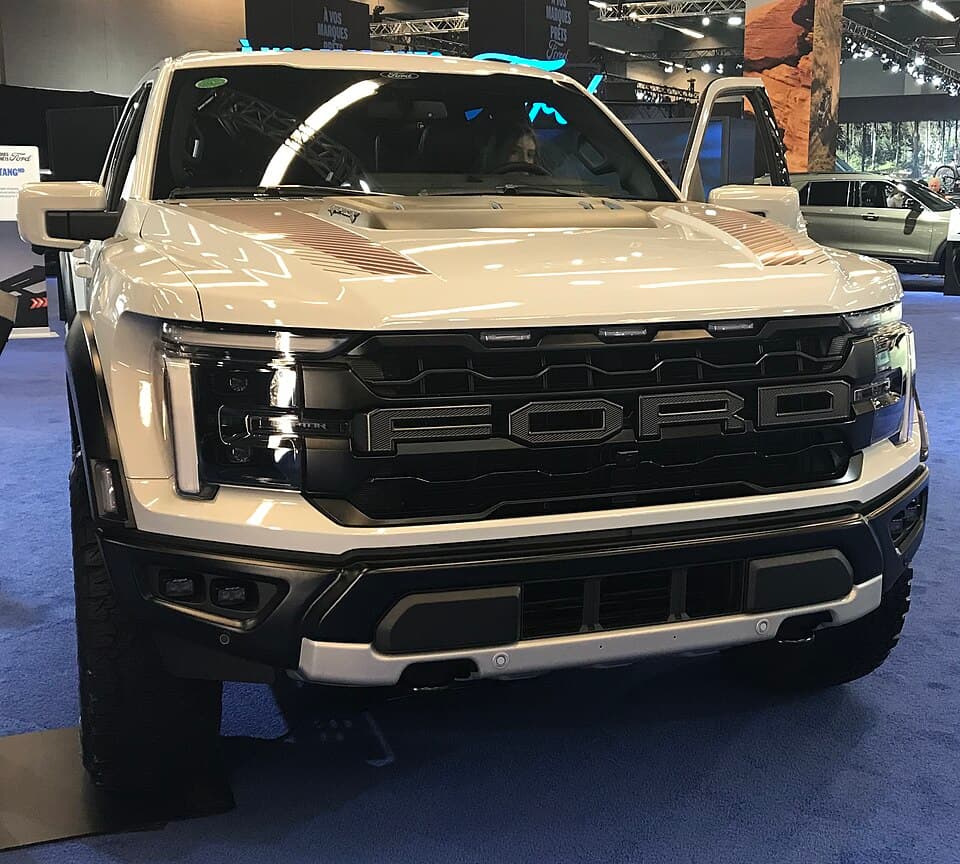 2026 Raptor on the Ford stand at the Montréal International Auto Show, head-on — the current facelift grille with the illuminated FORD lettering.
