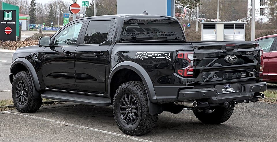 Black next-gen Ranger Raptor (P703) photographed in Böblingen, Germany, rear three-quarter — bedside RAPTOR lettering and the side-exit exhaust.