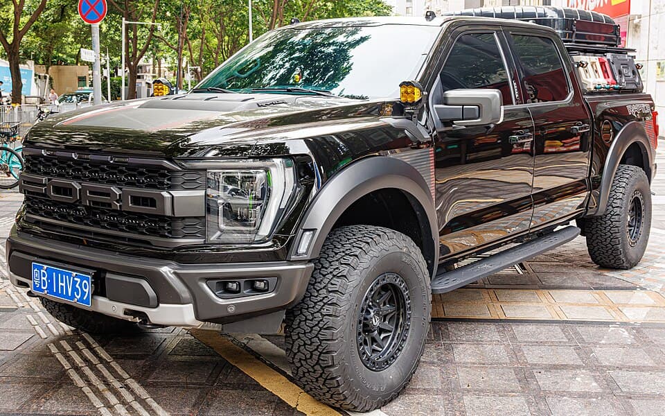 Black Raptor R built as an overlander, front three-quarter on a street in China with auxiliary pods, rock sliders and a roof rack.