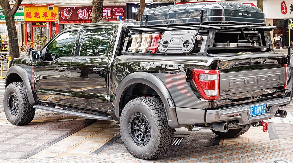 Rear three-quarter of the same black Raptor R in China, showing the RAPTOR R bedside badge with the red R and the quad exhaust outlets.